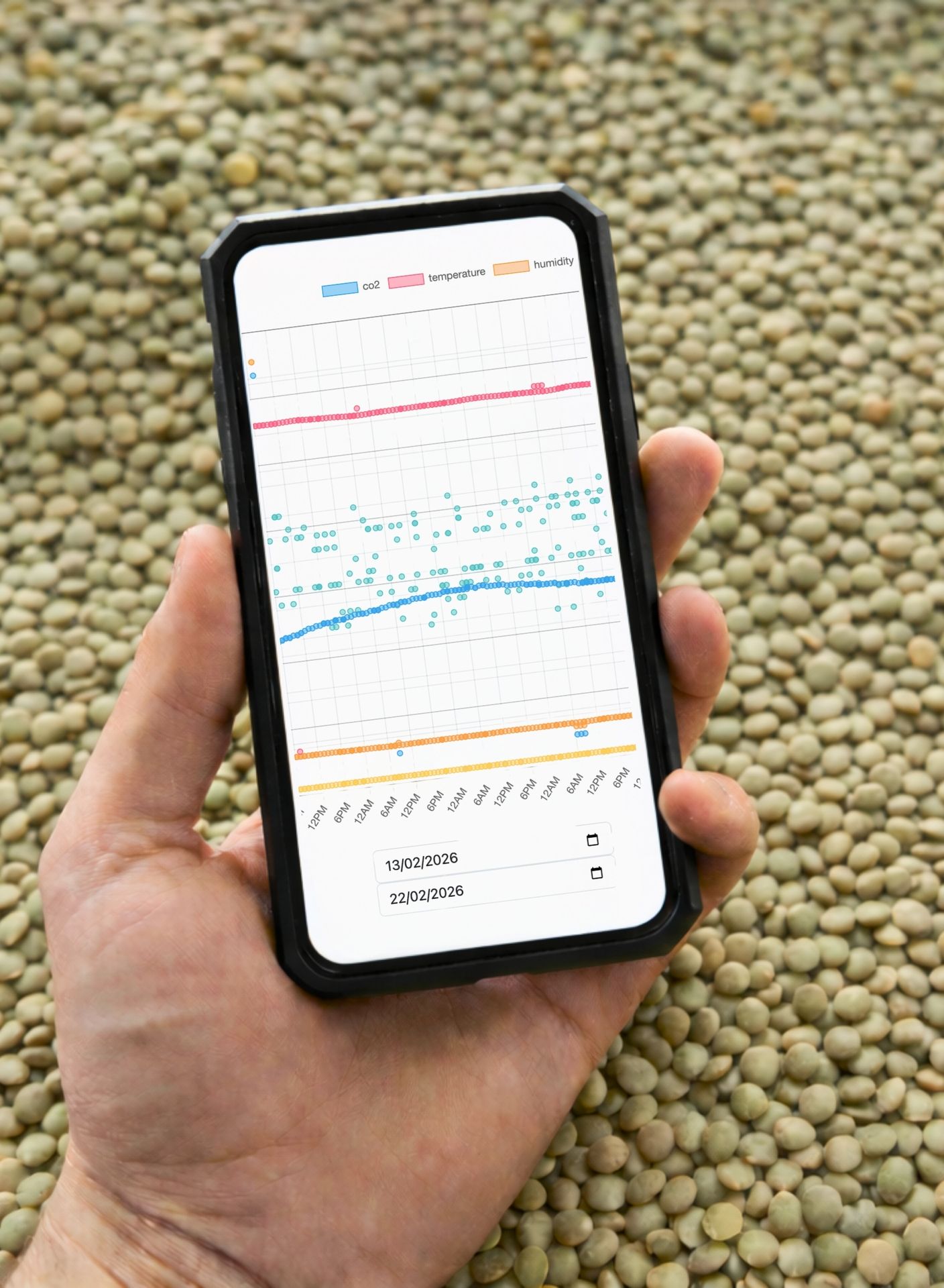 Operatore con smartphone e app Nox Control System per monitoraggio in tempo reale di CO₂, temperatura e umidità del grano