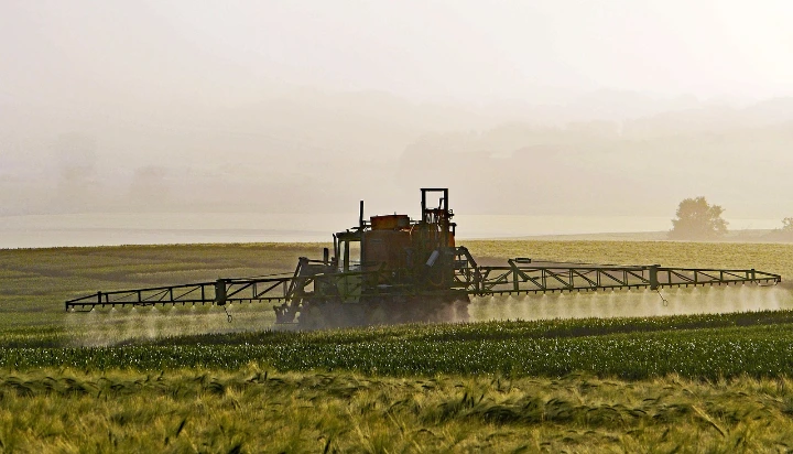 An agricultural sprayer operates in a lush, misty field during a golden sunrise, capturing the essence of modern farming techniques and rural landscapes An agricultural sprayer operates in a lush, misty field during a golden sunrise, capturing the essence of modern farming techniques and rural landscapes